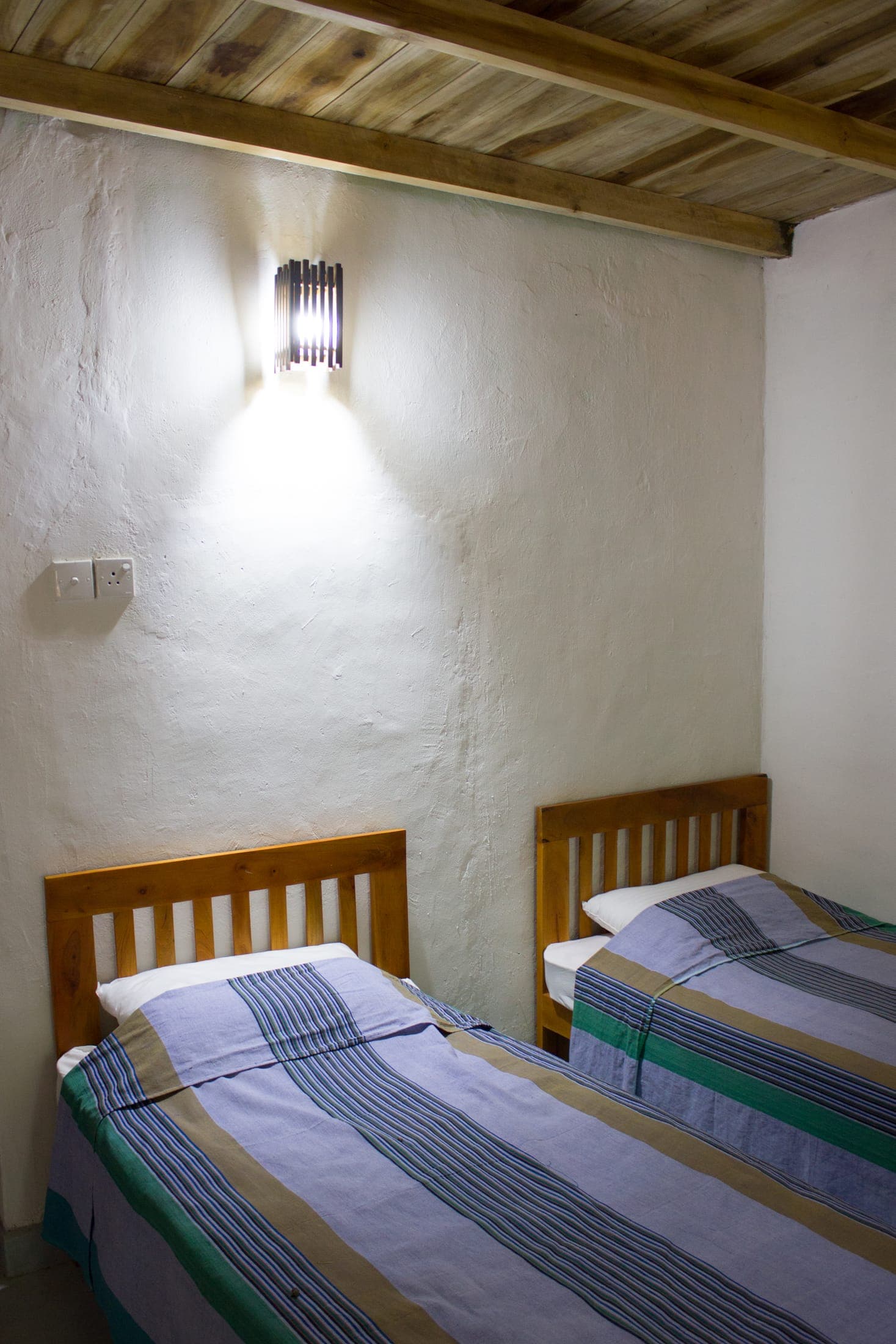 Second twin bedroom with two wooden beds under a wall light