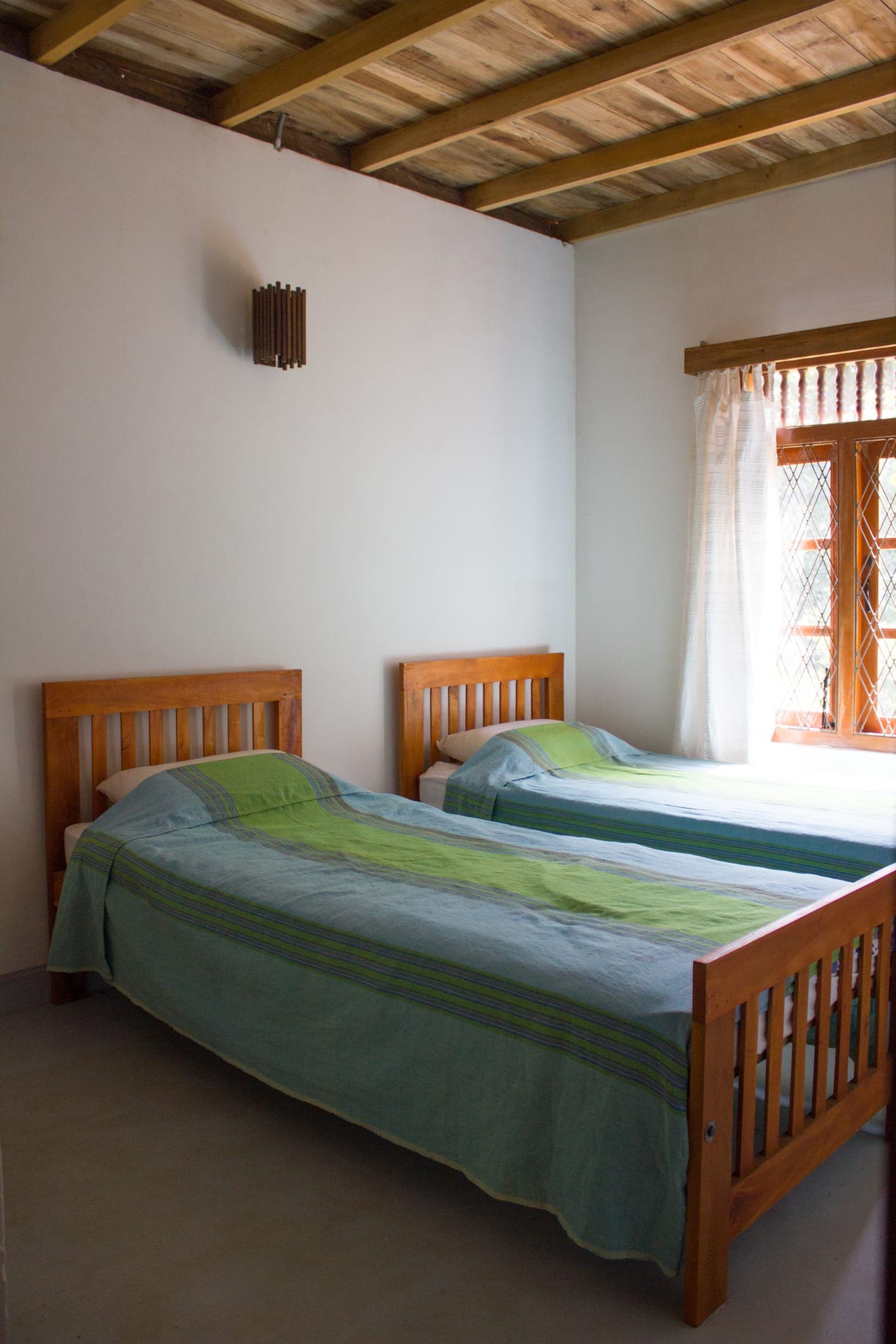 Twin bedroom with two long wooden beds and green bedspreads