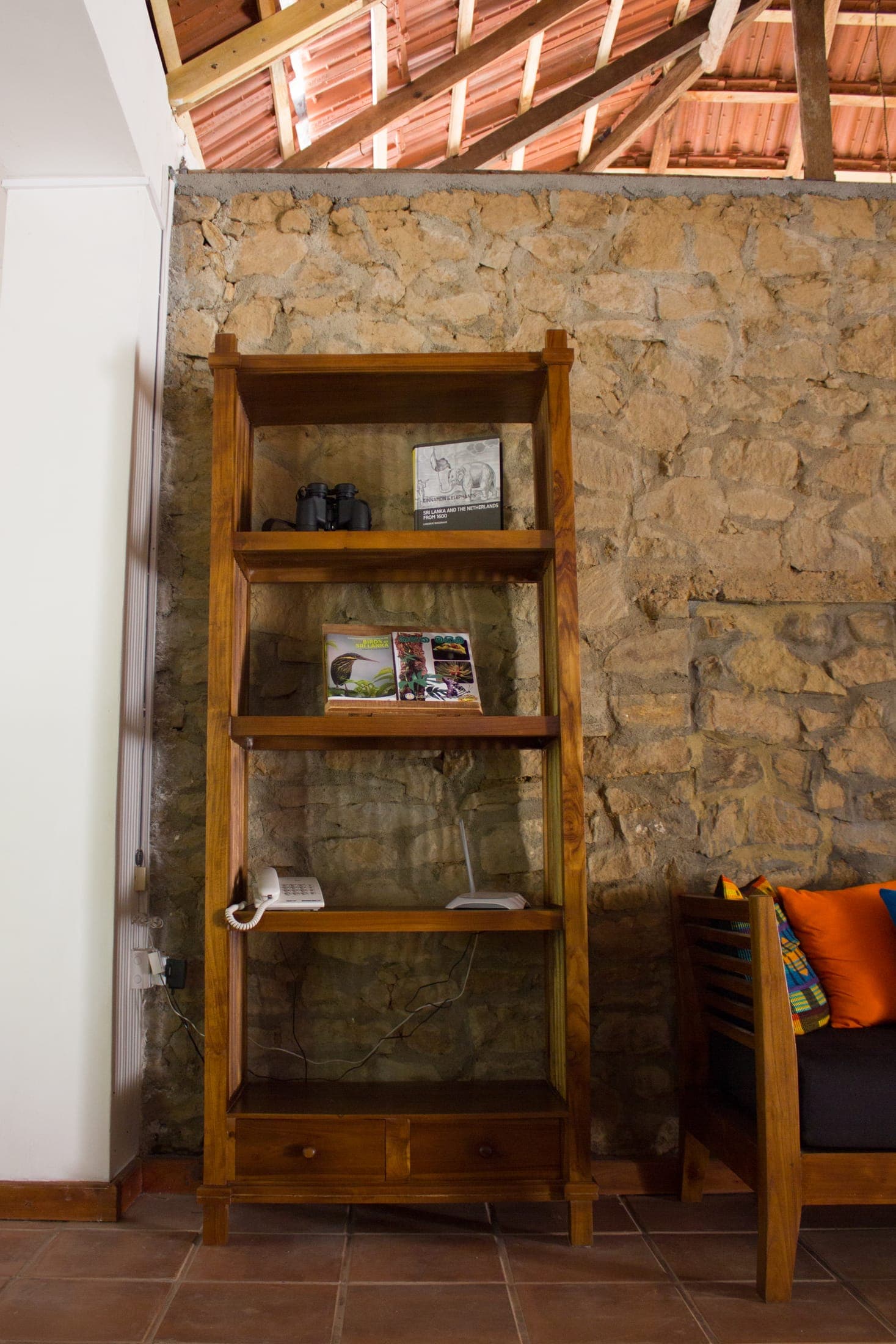 Wooden bookshelf with guidebooks against the original stone wall