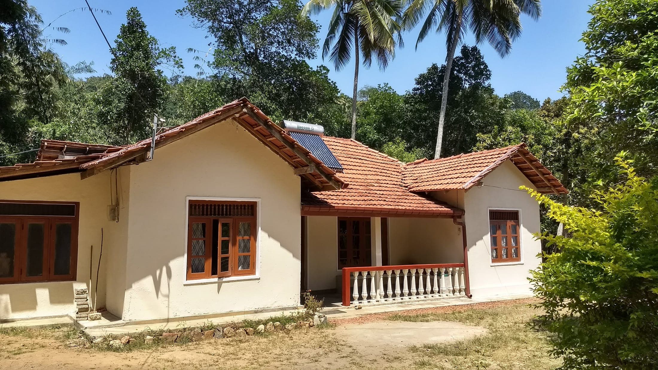 The cottage and solar water heater on the roof, seen across the front garden