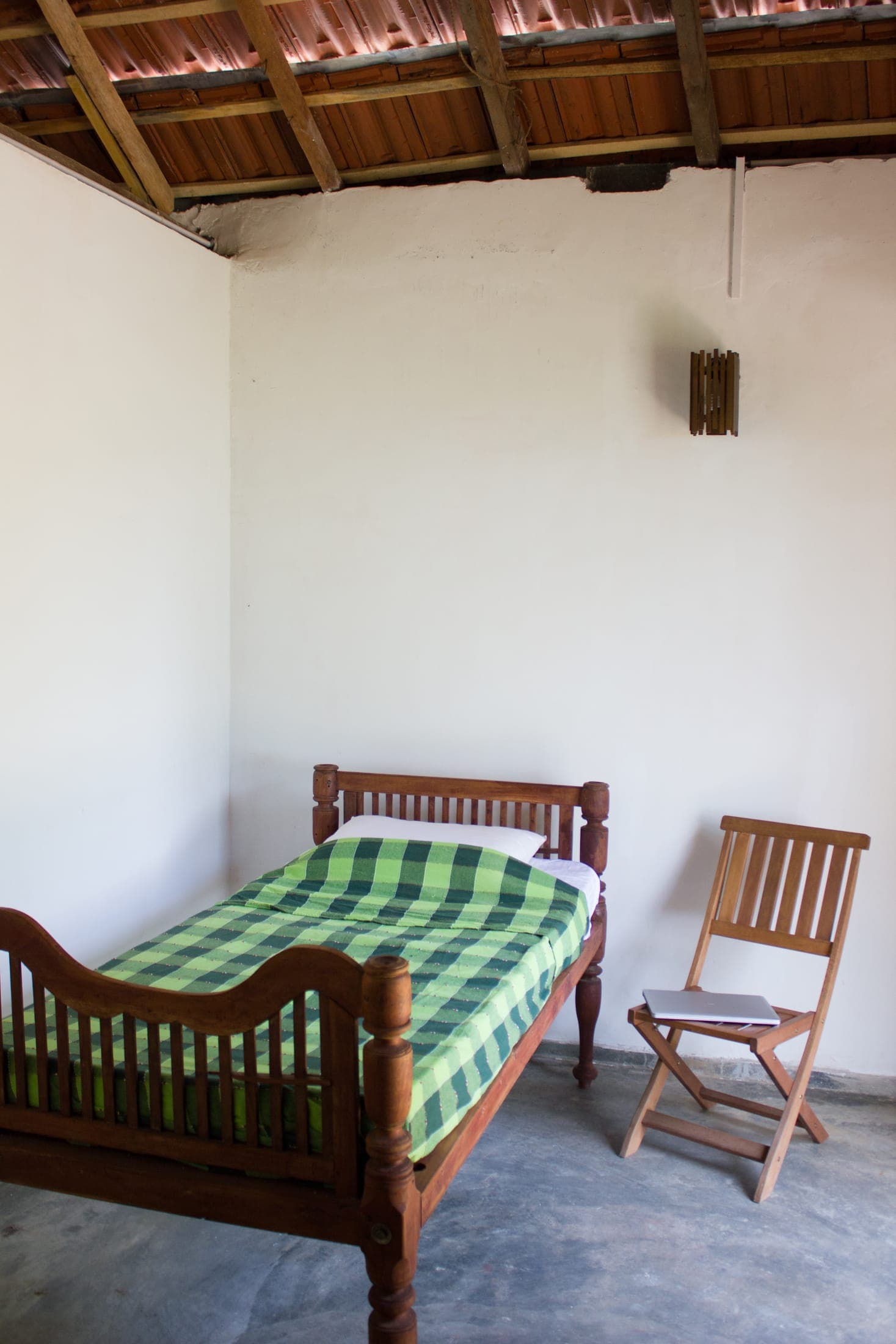 Small garden room with a single wooden bed and a green checked cover