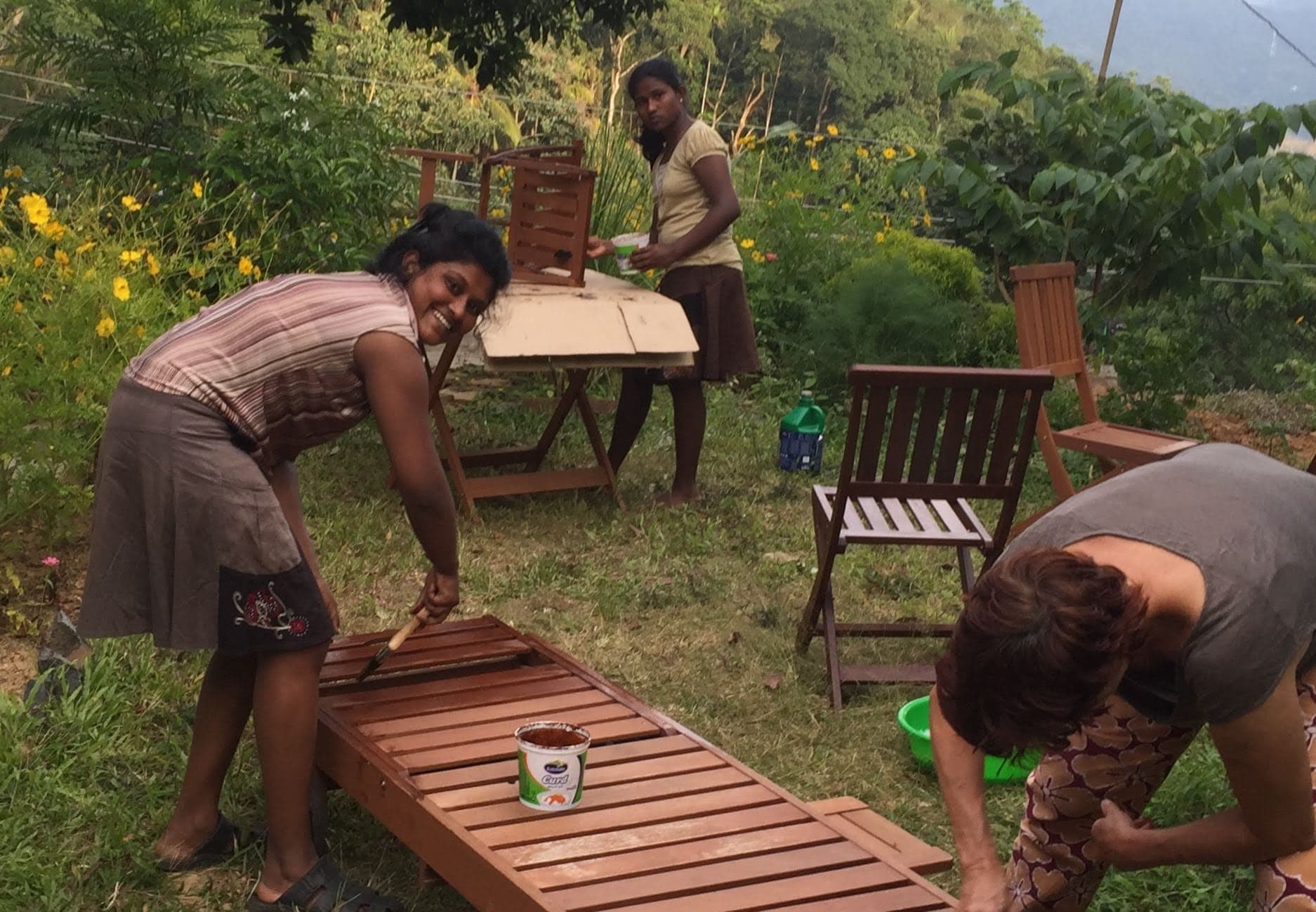 Neighbours helping to paint the wooden garden furniture
