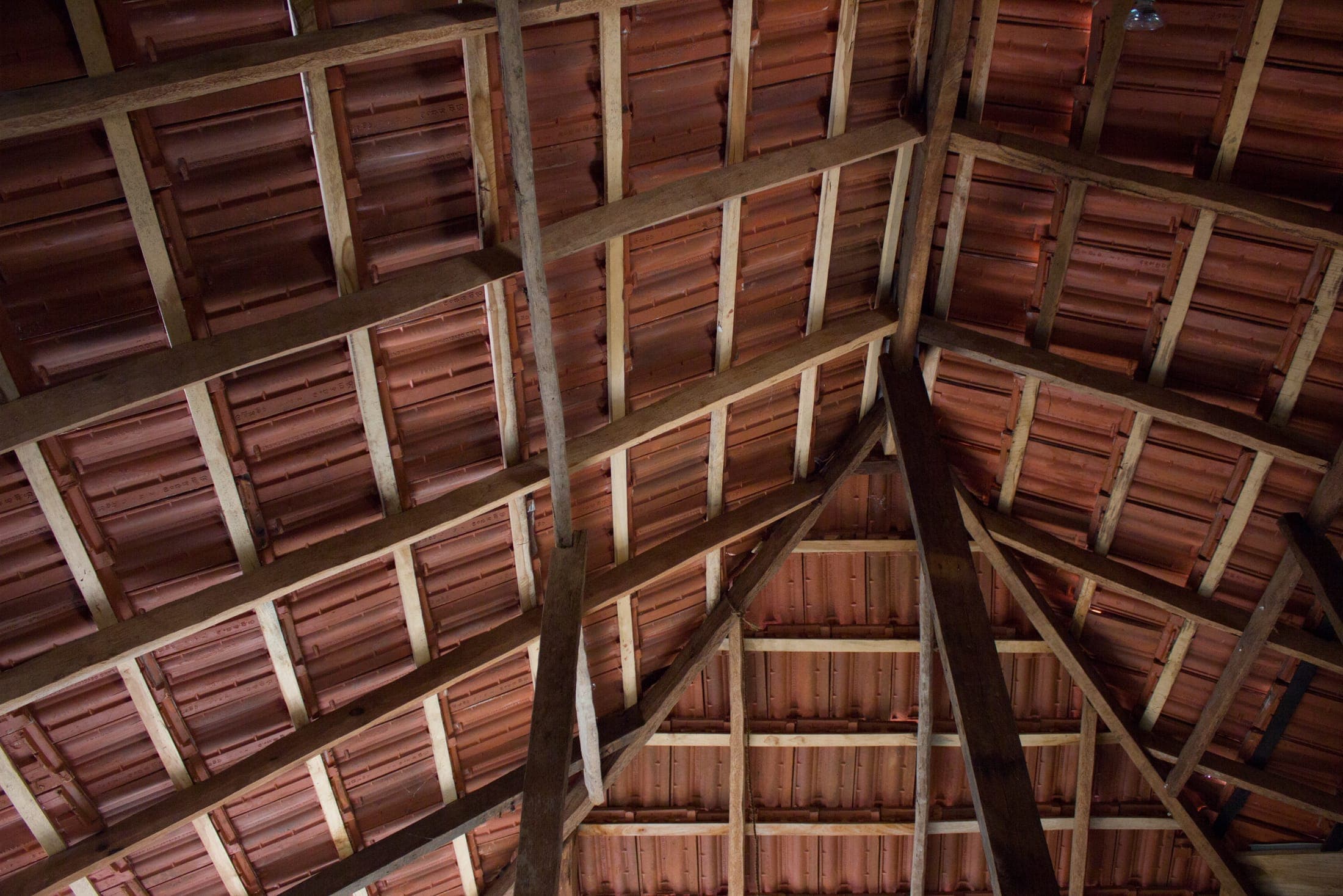 The exposed timber roof structure and terracotta tiles seen from inside