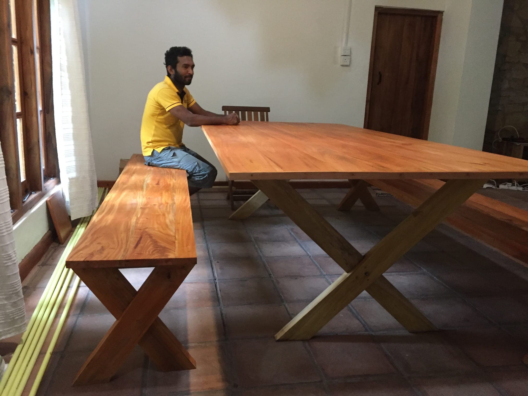 A long handmade wooden table and bench by Rukman, the village carpenter