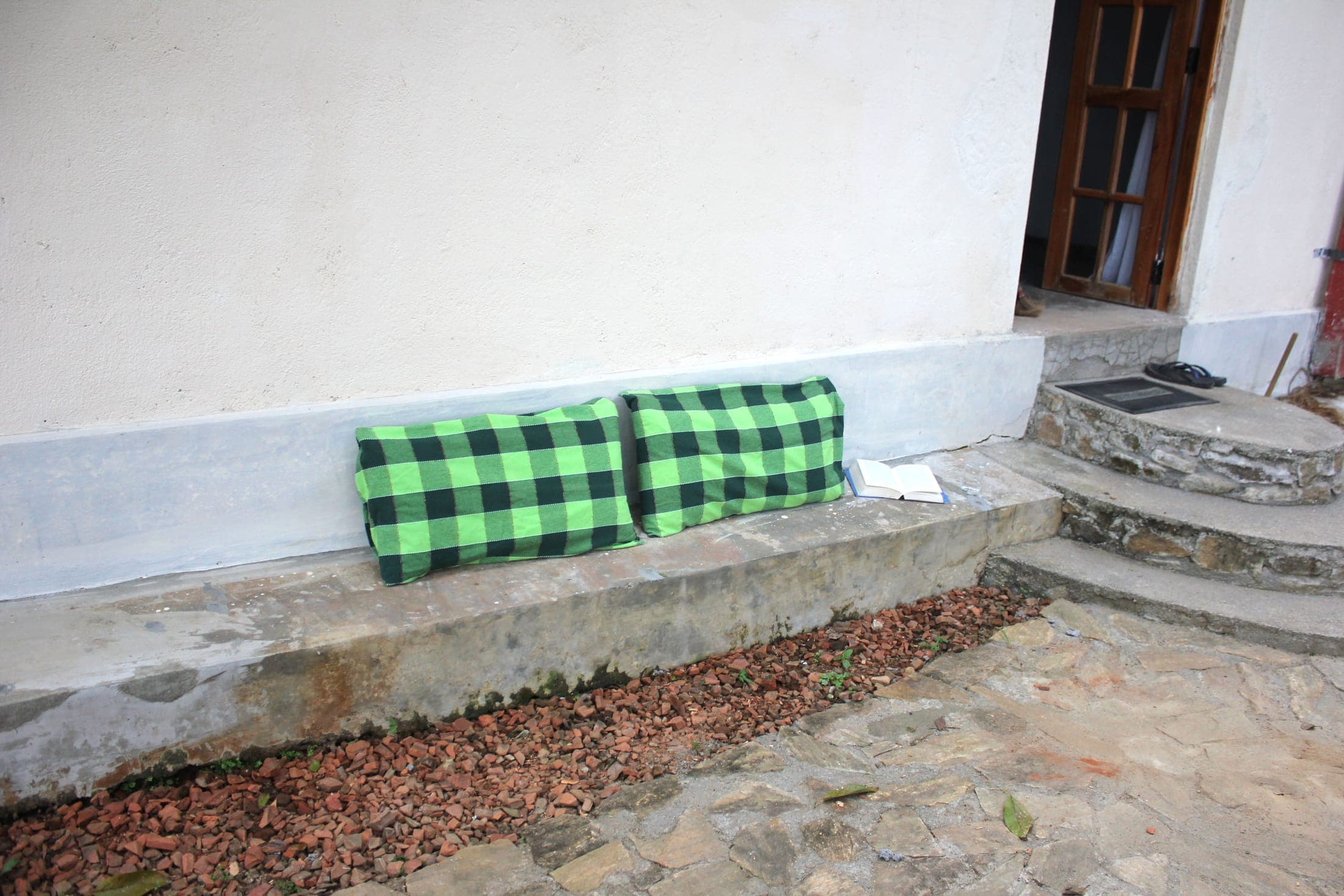 Low wall seating with green checked cushions beside the cottage entrance
