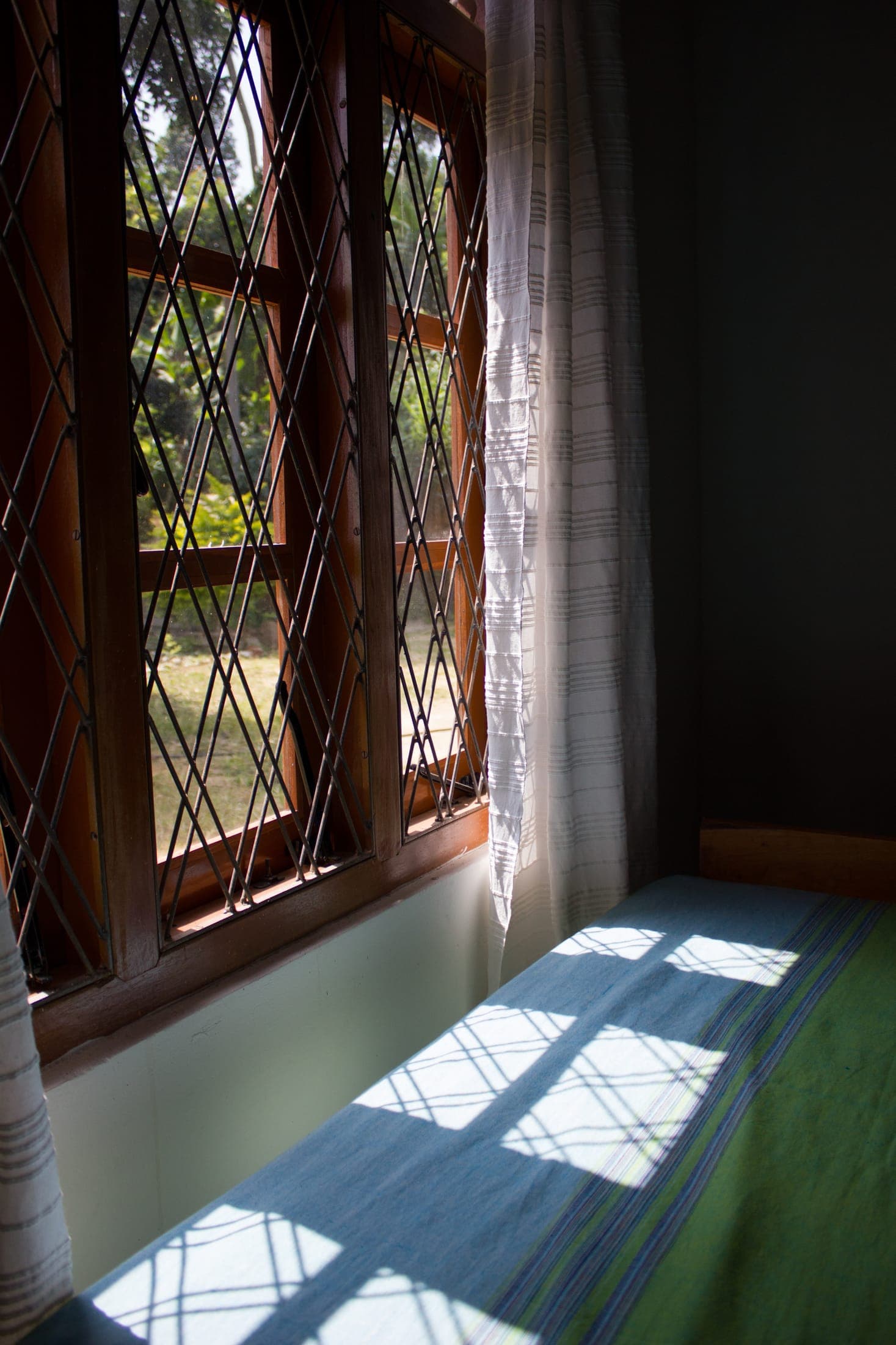 Sunlight through a diamond-lattice window onto a bed