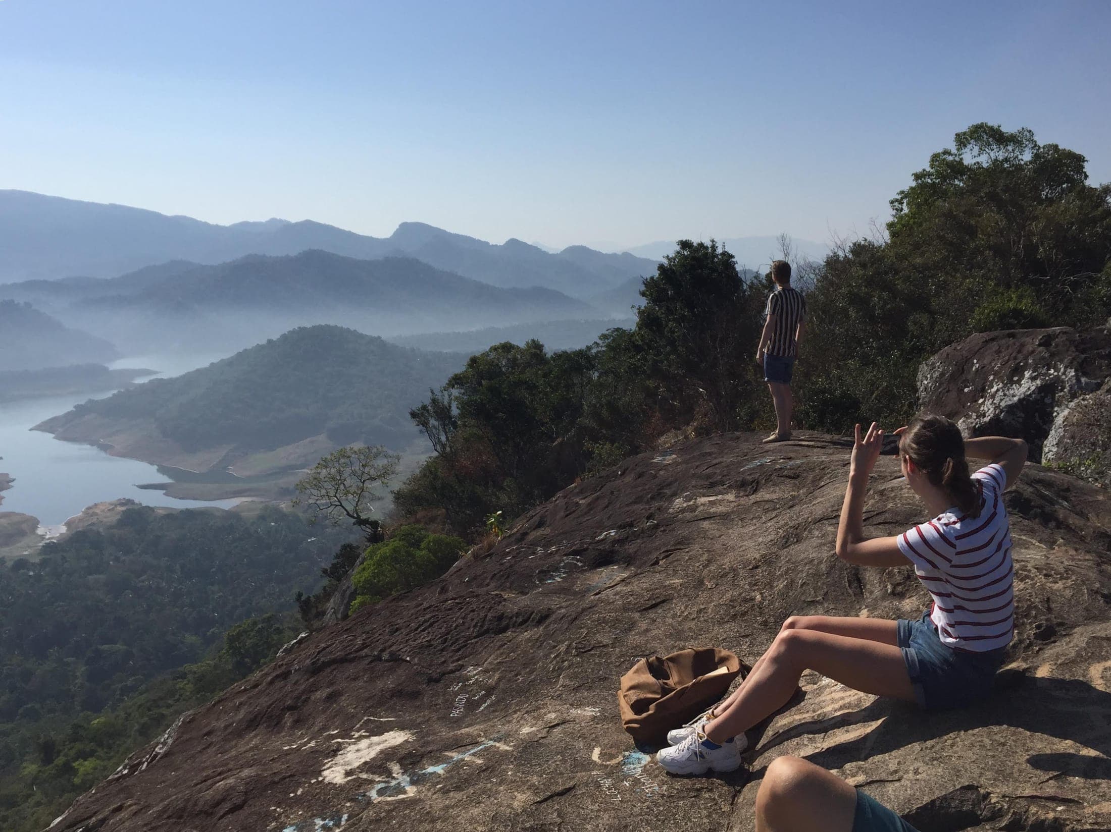 A hiker resting on Pettigala Rock above misty Victoria Lake