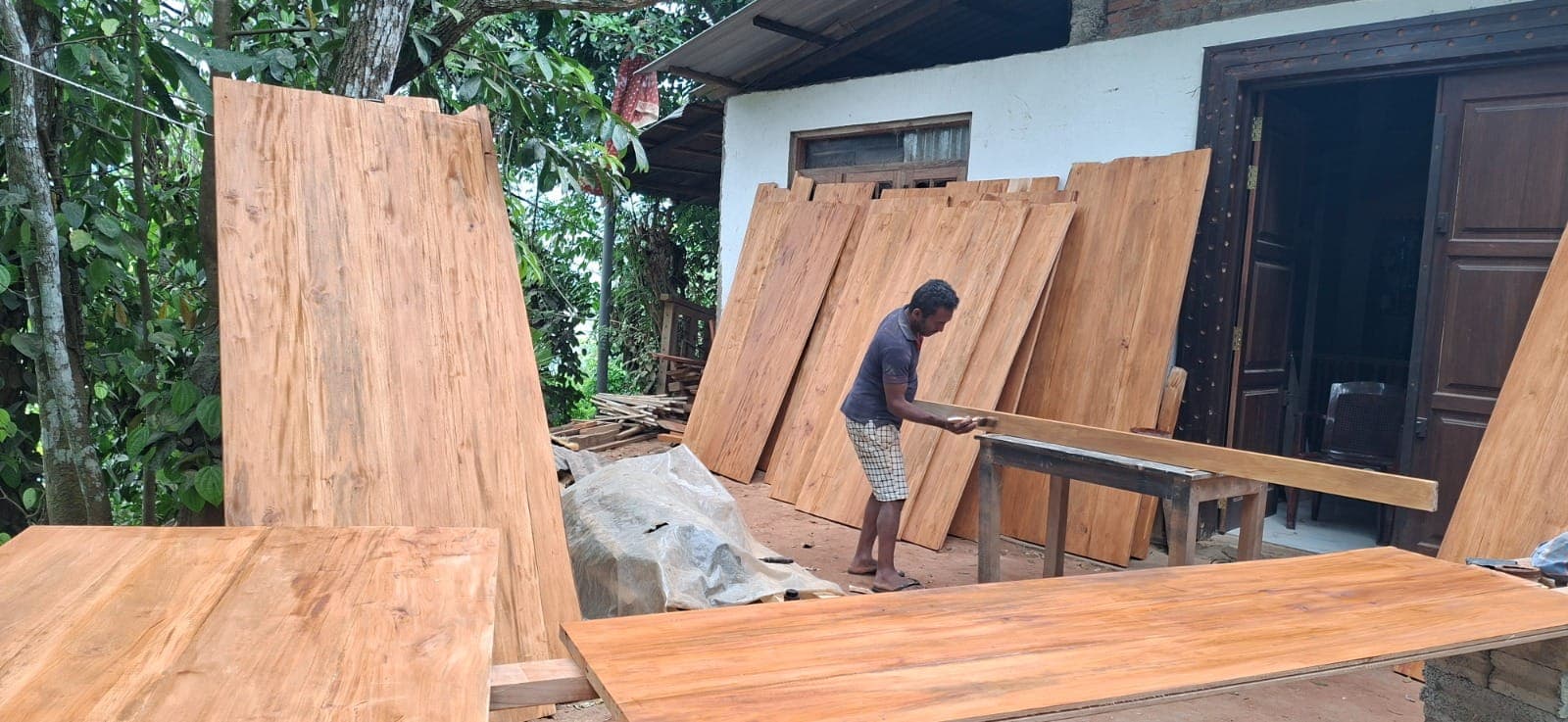 Rukman the carpenter moving freshly planed boards in his village workshop
