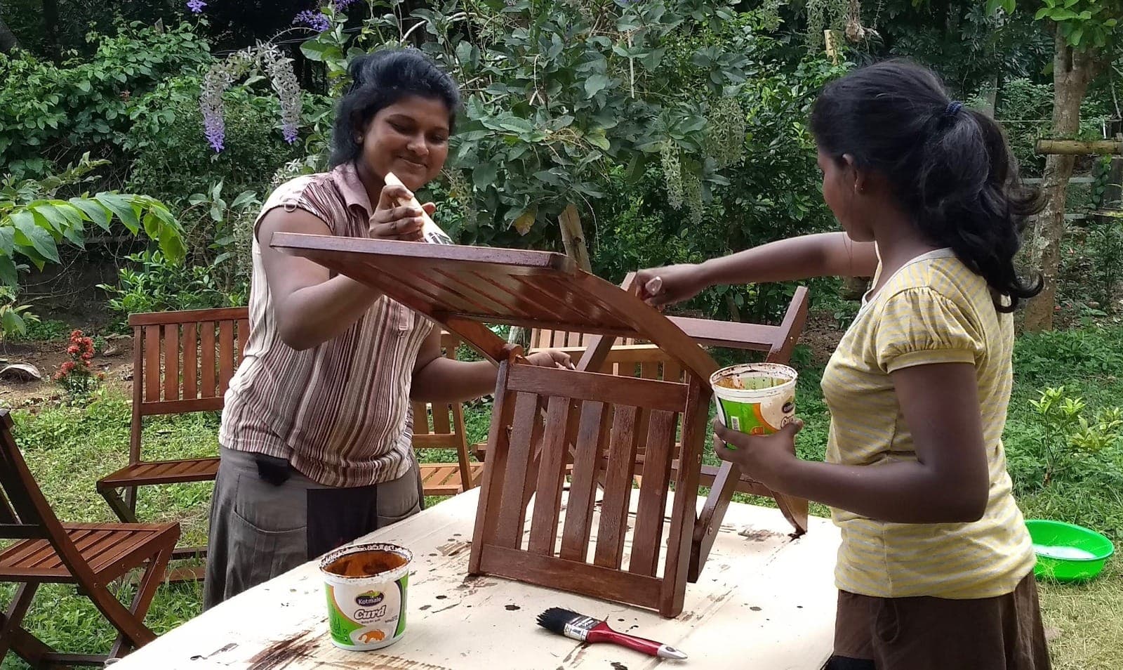 Sanduni and her sister Piumi painting a garden chair together