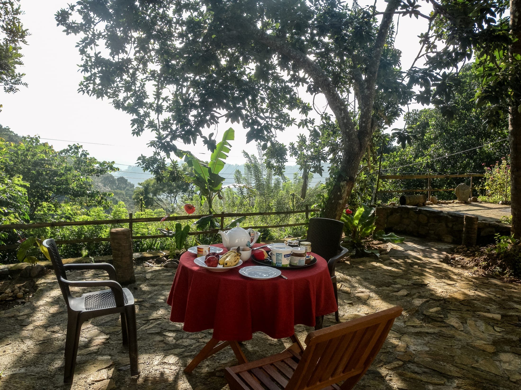 Breakfast laid out on a red tablecloth on the terrace, with a view over the valley